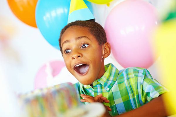 Portrait of an African American kid with a surprise expression looking at cake