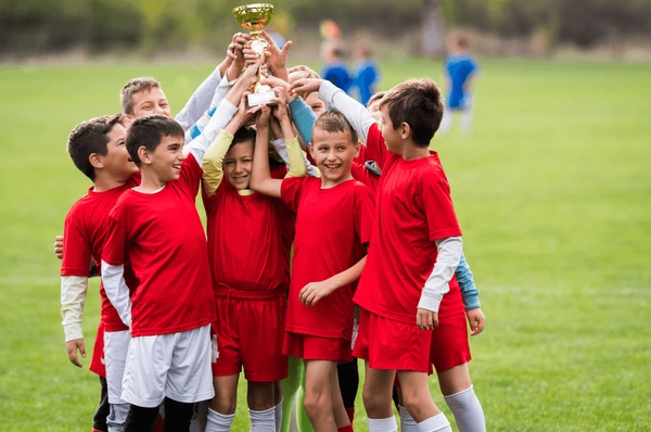 A group of boys in football wear enjoy celebrating their win together by smiling and laughing.