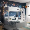 Jubilee L Shaped Triple Bunk Bed - White with Shelves Seeking a space-efficient sleeping arrangement? The Jubilee L Shaped Triple Bunk Bed in White offers an ideal solution. This configuration provides two distinct sleeping areas while maximizing available floor space for additional furnishings. This bed's design incorporates multifunctional elements. The upper bunk includes an integrated storage shelf, and the lower bunk features a desk area suitable for work or study. The underbed component is also freestanding, allowing for flexible placement and potential addition of under-bed storage. The neutral white finish ensures aesthetic compatibility with a variety of bedroom decors. The ladder is reversible, permitting assembly on either the left or right side of the bed. Key Features and Benefits: L-shaped triple bunk bed configuration with single and small double bed sizes Integrated shelving on the upper bunk Wide steps designed for convenient access to the upper bunk